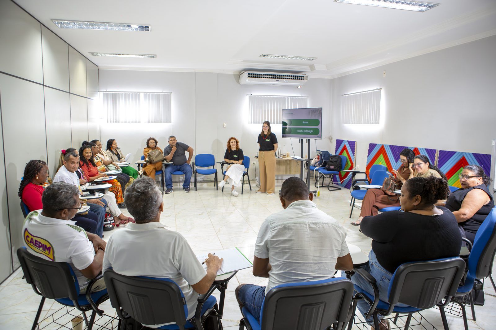 Participantes sentados em uma grande roda na sala da oficina, enquanto a equipe do Instituto Jataí, de pé ao fundo, abre o encontro.