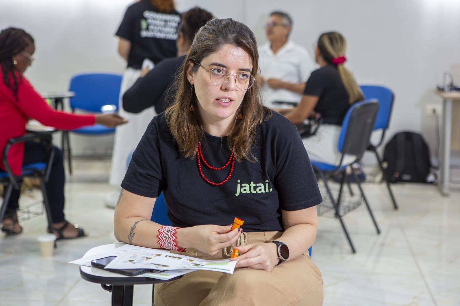 Integrante da equipe do Instituto Jataí, sentada, segura um carimbo e fala olhando para o lado.